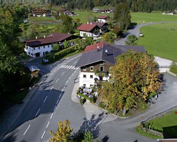 Eine malerische Dorfansicht mit traditionellen Häusern und einer ruhigen Straße. Die Umgebung ist grün und von Bäumen umgeben.