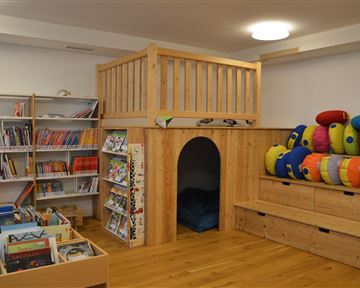 An inviting room with a reading area, bookshelves, and a cozy retreat. Colorful cushions provide seating and relaxation space.