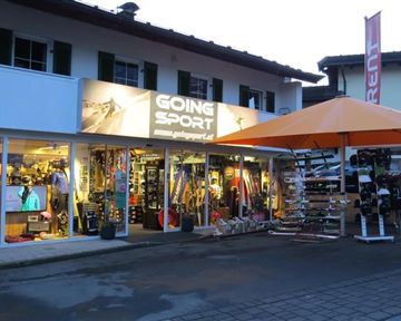 A sports store with colorful sports items and equipment. There is a large orange umbrella in front of the shop.