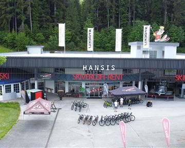 Ein Geschäft für Sportartikel mit Fahrradverleih und Ski-Ausrüstung. Draußen stehen mehrere Fahrräder und Zelte.