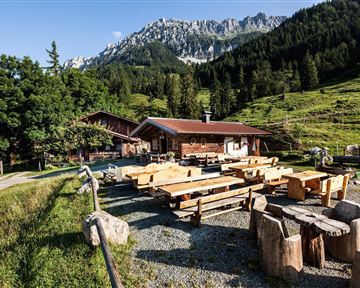 A cozy mountain hut in a mountainous landscape. Wooden tables and benches invite you to linger.