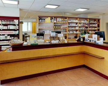 Eine helle Apotheke mit Regalen voller Medikamente. Der Empfangstresen ist gut sichtbar und freundlich gestaltet.