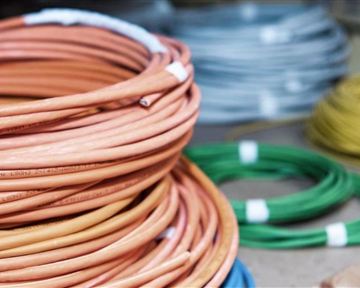 Bunte Kabelrollen in verschiedenen Farben liegen auf einem Tisch. Die Kabel sind ordentlich aufgerollt und gut sichtbar.