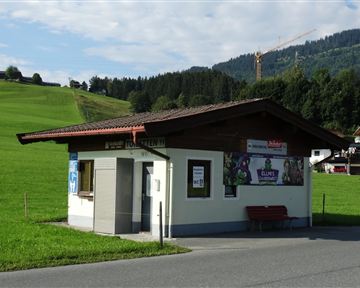 A small sales building in a rural setting. In the background, green meadows and mountains can be seen.