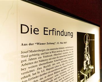 Eine Ausstellungstafel mit dem Titel „Die Erfindung“. Der Text enthält Informationen über Josef Madersberger und seine Erfindung, datiert auf den 12. Mai 1917.