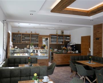 A modern café with wooden interiors and cozy seating areas. The display showcases a selection of food and drinks.
