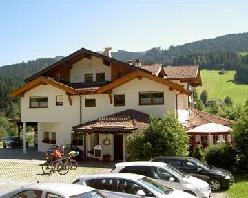 A cozy café with a charming alpine design. In the background, green meadows and forests can be seen.