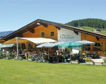 An inviting restaurant with a terrace under sun umbrellas. Many guests enjoy the view of the surrounding nature.