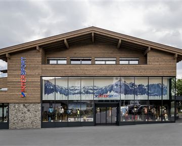 A modern building with wooden cladding and large windows. In the background, there is a mountain motif.