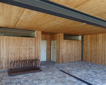 A modern room with wood paneling and a bright ceiling. On the left, there is a bike rack and two doors.