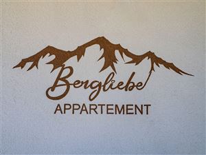 A decorative sign with the inscription "Mountain Love Apartment" above stylized mountains. The design conveys a cozy and inviting atmosphere.