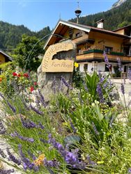 A beautiful farm named "Hof Alberts" is surrounded by colorful flowers and lavender. In the background, mountains and a blue sky are visible.