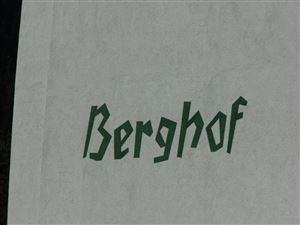 Ein Wandbild mit der Aufschrift "Berghof" in grüner Farbe. Der Hintergrund ist eine helle, neutrale Wand.