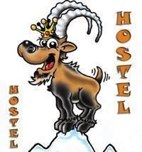 A funny mascot in the shape of a goat with a crown. The goat is standing on a mountain and is part of the logo of a hostel.