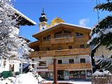 Ein wunderschönes Gebäude im alpinen Stil, umgeben von schneebedeckten Bäumen. Der klare blaue Himmel vervollständigt die winterliche Landschaft.