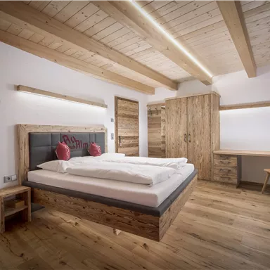 A modern bedroom with wooden furniture and a large bed. The room has bright walls and a pleasant atmosphere.