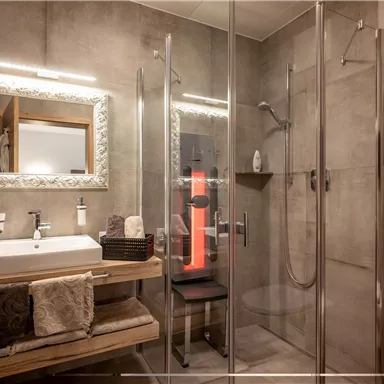 Ein modernes Badezimmer mit Glasdusche und hellen Holzdetails. Der Spiegel und die Waschbeckenarmatur sorgen für eine stilvolle Atmosphäre.