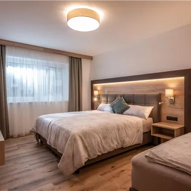 Ein modernes Hotelzimmer mit zwei Betten und weichen Bettdecken. Große Fenster sorgen für viel Licht und eine angenehme Atmosphäre.