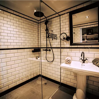 Ein modernes Badezimmer mit weißen Fliesen und einer Duschkabine. Im Raum sind Handtücher und ein Waschbecken vorhanden.