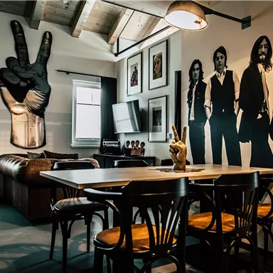 A stylish living room with a leather sofa and a dining table. On the wall are sophisticated graphics and black-and-white photos of people.