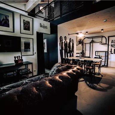 A modern room with a leather sofa and a large table. Pictures and an inspiring quote hang on the walls.