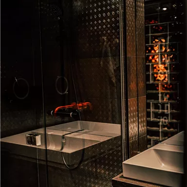 A modern bathroom with a glass shower and an elegant sink. The lighting creates a cozy atmosphere.