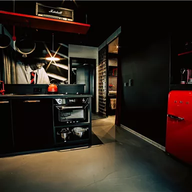 Eine moderne Küche mit schwarzen Möbeln und einem roten Kühlschrank. Die Ausstattung ist stilvoll und funktional.