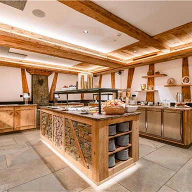 Eine moderne, einladende Frühstücksbar mit Holzdetails und warmem Licht. Der Raum ist geschmackvoll eingerichtet und bietet eine Vielzahl von Speisen.