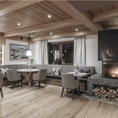 A cozy restaurant with wooden decor and elegant chairs. The fireplace creates a warm atmosphere.