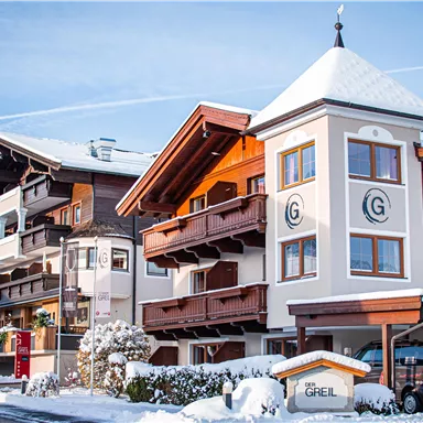 An attractive hotel building in the snow, surrounded by a picturesque winter landscape. Clear blue skies and snow-covered roofs create a serene atmosphere.