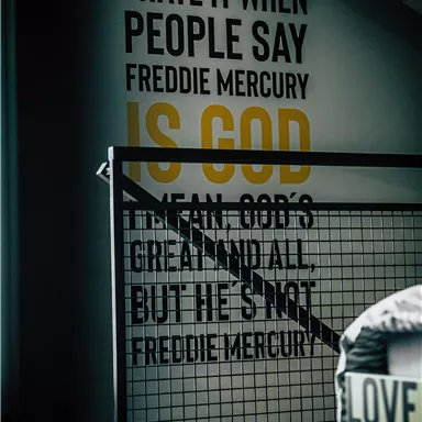 A modern room with a wall displaying text written in English. The text focuses on Freddie Mercury and contains a strong personal opinion.