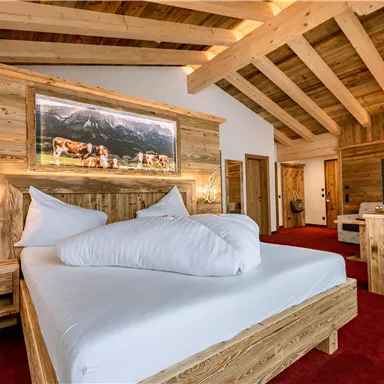 A modern bedroom with wooden decor and a large bed. The warm colors and creative lighting create a cozy atmosphere.