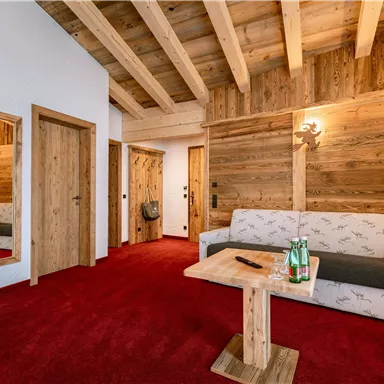 A cozy room with a red carpet and wooden walls. There is a sofa, a table, and large mirrors.