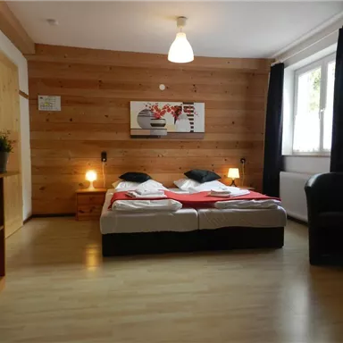 Ein gemütliches Schlafzimmer mit einem Doppelbett und Holzvertäfelungen. Das Zimmer ist hell und modern eingerichtet, mit einem Schreibtisch und einem großen Fenster.