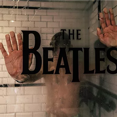 Ein verschwommener Blick auf eine Person hinter einer Duschwand mit der Aufschrift "The Beatles". Die Hände der Person sind auf die Scheibe gedrückt.