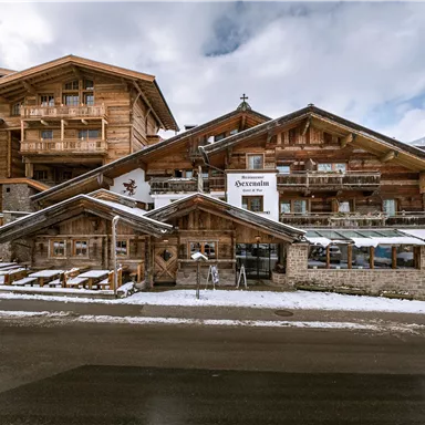 Ein charmantes Holzgebäude in alpinem Stil, umgeben von Schnee. Die Region wirkt einladend und gemütlich.
