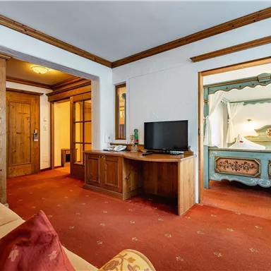 Ein gemütliches Zimmer mit Holzmöbeln und einem Fernseher. Die Einrichtung ist rustikal und hat eine warme Atmosphäre.