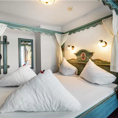 A cozy bedroom with a large bed and three decorative pillows. The beautiful walls and warm lights create an inviting atmosphere.