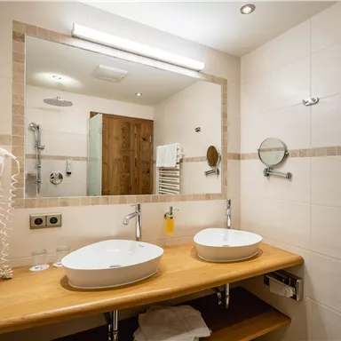 Ein modernes Badezimmer mit zwei Waschbecken und hellem, einladendem Design. Die Wände sind hell und die Ausstattung ist funktional.