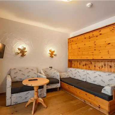 A cozy living room with wood paneling and a sofa. A round table and a television are also present.