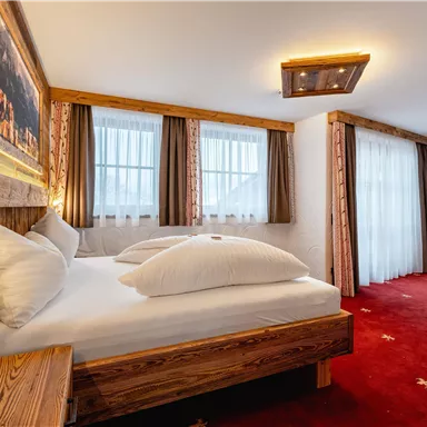 A cozy bedroom with wooden paneling and two beds.  

Large windows provide plenty of daylight, and a modern TV corner is also available.