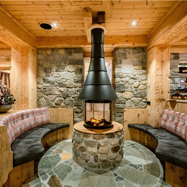 Eine gemütliche Sitzecke mit einem modernen Kamin in einem Holz- und Steindesign. Die Atmosphäre ist warm und einladend.