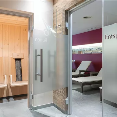 A modern wellness area with glass doors. On the left side, there is a sauna, while the room on the right invites you to relax.