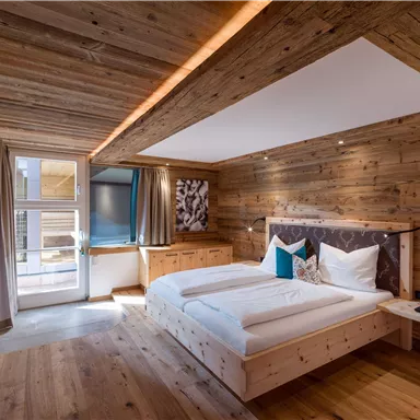 Ein modernes Schlafzimmer mit Holzverkleidung und komfortablen Betten. Große Fenster sorgen für viel Licht und einen einladenden Ausblick.