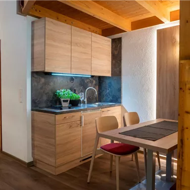 Eine moderne Küche mit Holzschränken und einem kleinen Essbereich. Der Raum hat eine helle, einladende Atmosphäre.