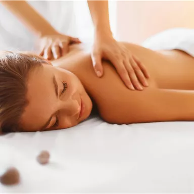 Eine entspannende Massage wird einer Frau auf einer Liege gegeben. Sie genießt die Behandlung in einer ruhigen Umgebung.