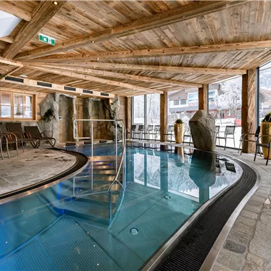 Ein moderner Poolbereich mit Holzelementen und großen Fenstern. Der Raum bietet einen einladenden Blick auf die Landschaft draußen.