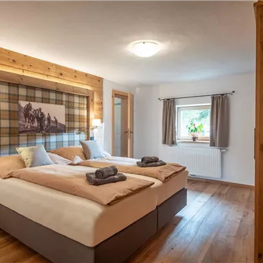 Ein modern eingerichtetes Zimmer mit zwei Betten und Holzdetails. Es gibt eine gemütliche Atmosphäre mit einem Fenster und einem Fernseher an der Wand.