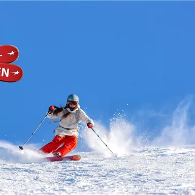 A person is skiing on a snow-covered slope under a clear blue sky. In the background, there is a sign that reads "SUPER SKI WEEKS."
