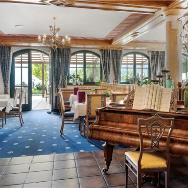 An elegant restaurant with wooden-paneled walls and stylish tables. Large windows provide plenty of daylight and a view outside.